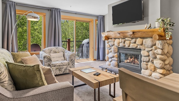 A living room with a fireplace, a sofa, a coffee table, and a TV mounted on the wall.