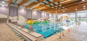 An indoor swimming pool with lanes, starting blocks, and a diving platform. - Creekside Condo | Main Street | Mountain Views (Canmore)