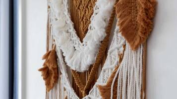 A macrame wall hanging with a wooden hanger.