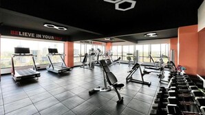 Une salle de sport équipée de tapis de course, d’appareils de musculation et d’haltères.
