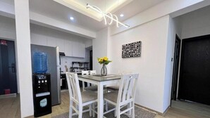 Une cuisine moderne avec des meubles blancs, un distributeur d’eau et un coin repas comprenant une table et des chaises.