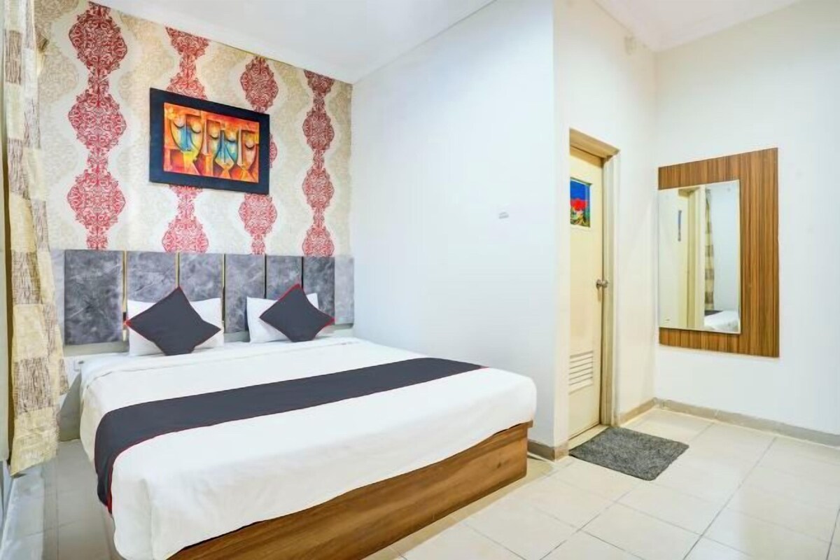 Une chambre d’hôtel avec un lit, une œuvre d’art accrochée au mur, une porte et un miroir.