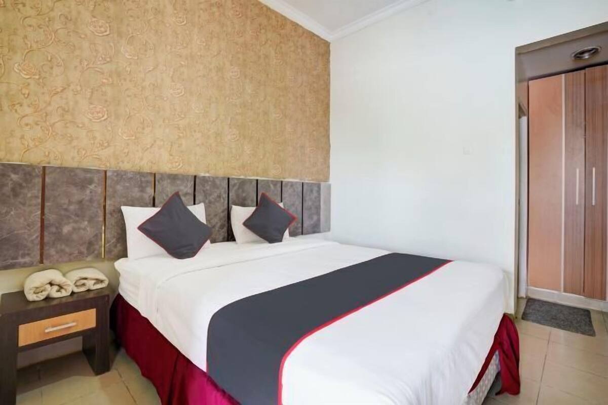 A hotel room with a bed, a nightstand, a wardrobe, and a patterned wall.