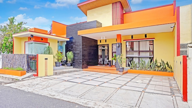 Una casa moderna de dos pisos con techo plano, ventanas amplias y entrada con azulejos.