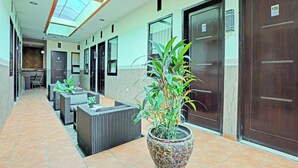 Un pasillo de hotel con una larga recepción, puertas de madera oscura y una planta grande en maceta.