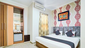 Una habitación de hotel con cama, armario, un refrigerador pequeño y cortina de ducha.