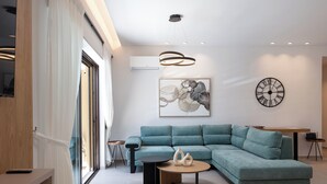 A modern living room with a teal sectional sofa, a round coffee table, and a minimalist decor style.