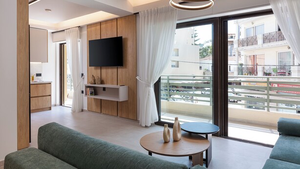 A modern living room with a sofa, a coffee table, and a flat-screen TV mounted on the wall.