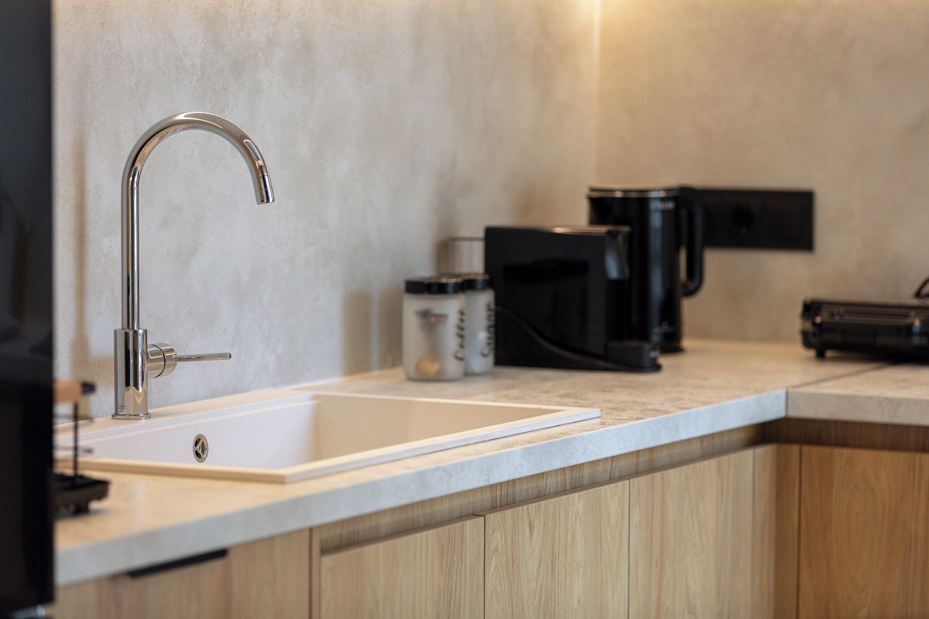 A modern kitchen with a stainless steel faucet, a coffee maker, and a sink.