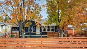 A single-story building with a porch, surrounded by trees with autumn foliage. - Vintage Vine House Retreat~ walk to Main St! (Murphys)