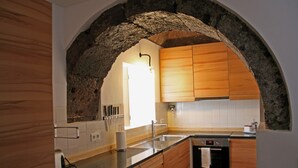 A kitchen with a stone arch, wooden cabinets, a stainless steel sink, and a built-in oven.