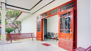 A spacious indoor area with a red door, a bench, and a tiled floor. - Hotel O Krakatau Near Universitas Muhammadiya Sumatra Utara ( UMSU ) (Medan)