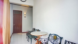A hallway with a wooden door, a clock, and a table with chairs. - Hotel O Krakatau Near Universitas Muhammadiya Sumatra Utara ( UMSU ) (Medan)