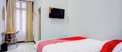 A hotel room with a bed, a desk, and a TV.