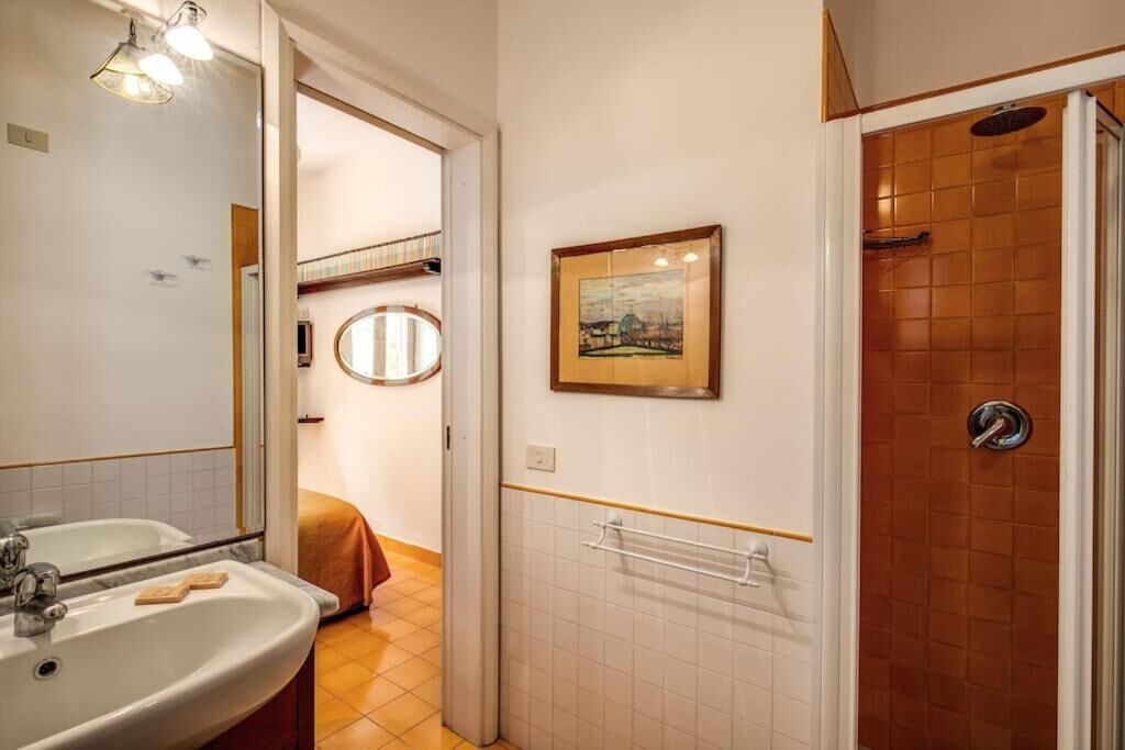 Ein Badezimmer mit zwei Waschbecken, einer Dusche, einem Handtuchhalter und einem gerahmten Bild an der Wand.
