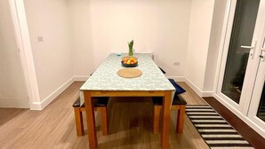 Un comedor con una mesa, sillas, un cuenco de fruta y un tapete.