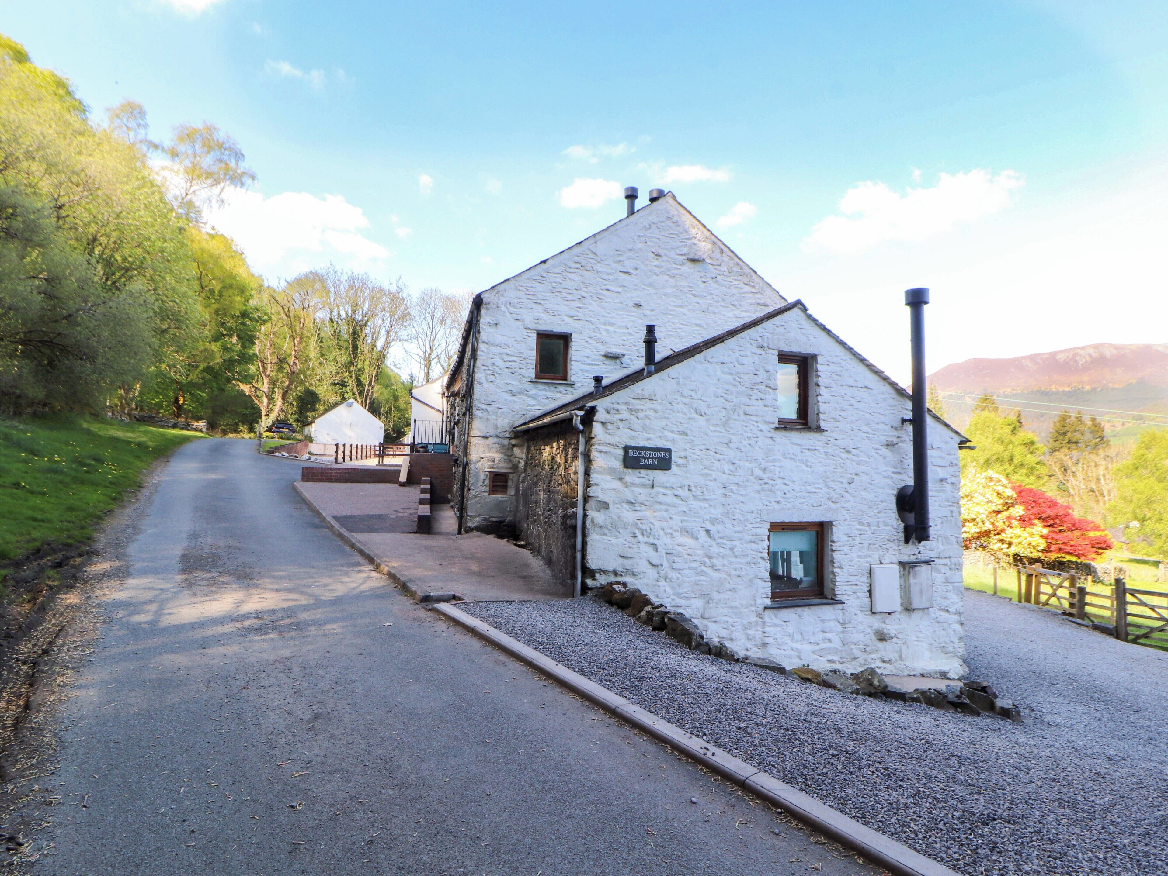A white stone building with a sign reading 'Beckstones Barn' on a rural road.