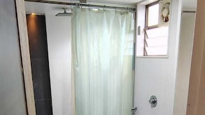 A small bathroom with a toilet, a glass shower enclosure, and a sink. - Sai Kan Hotel (Shirdi)