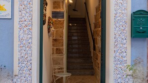 Una entrada estrecha con un muro de mosaicos de cerámica, una escalera y un pequeño rincón con asientos.