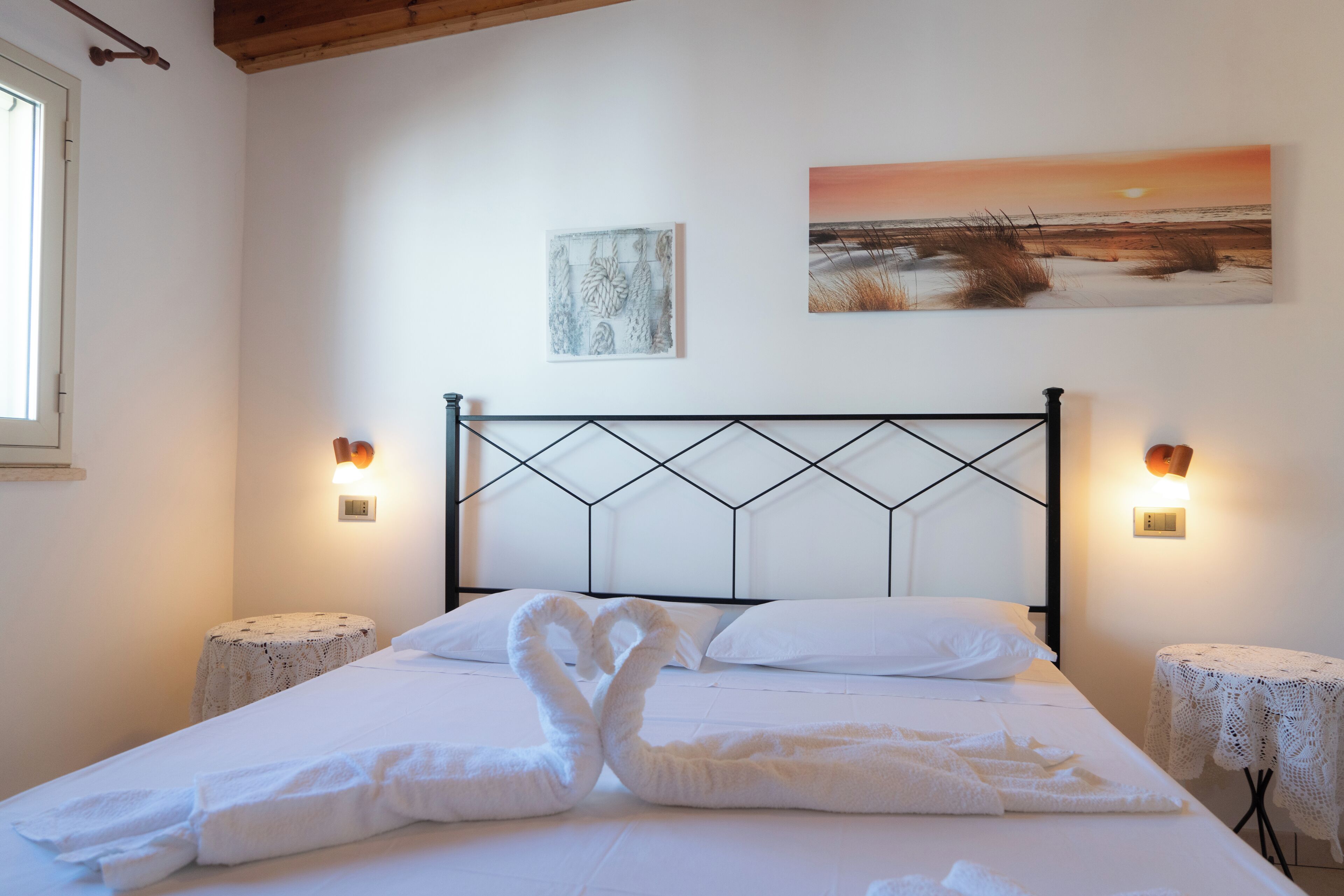 Een slaapkamer met een bed, twee nachtkastjes, een hoofdbord, wanddecoratie en een raam.