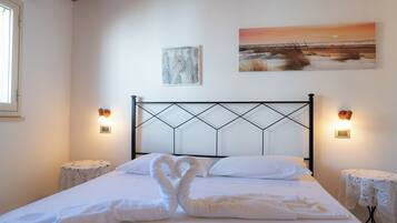 Een slaapkamer met een bed, twee nachtkastjes, een hoofdbord, wanddecoratie en een raam.