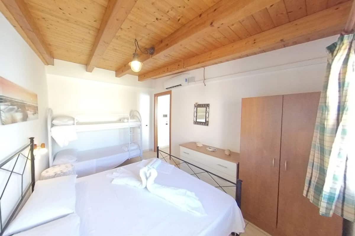A room with a bunk bed, a wooden wardrobe, and a bedside table.