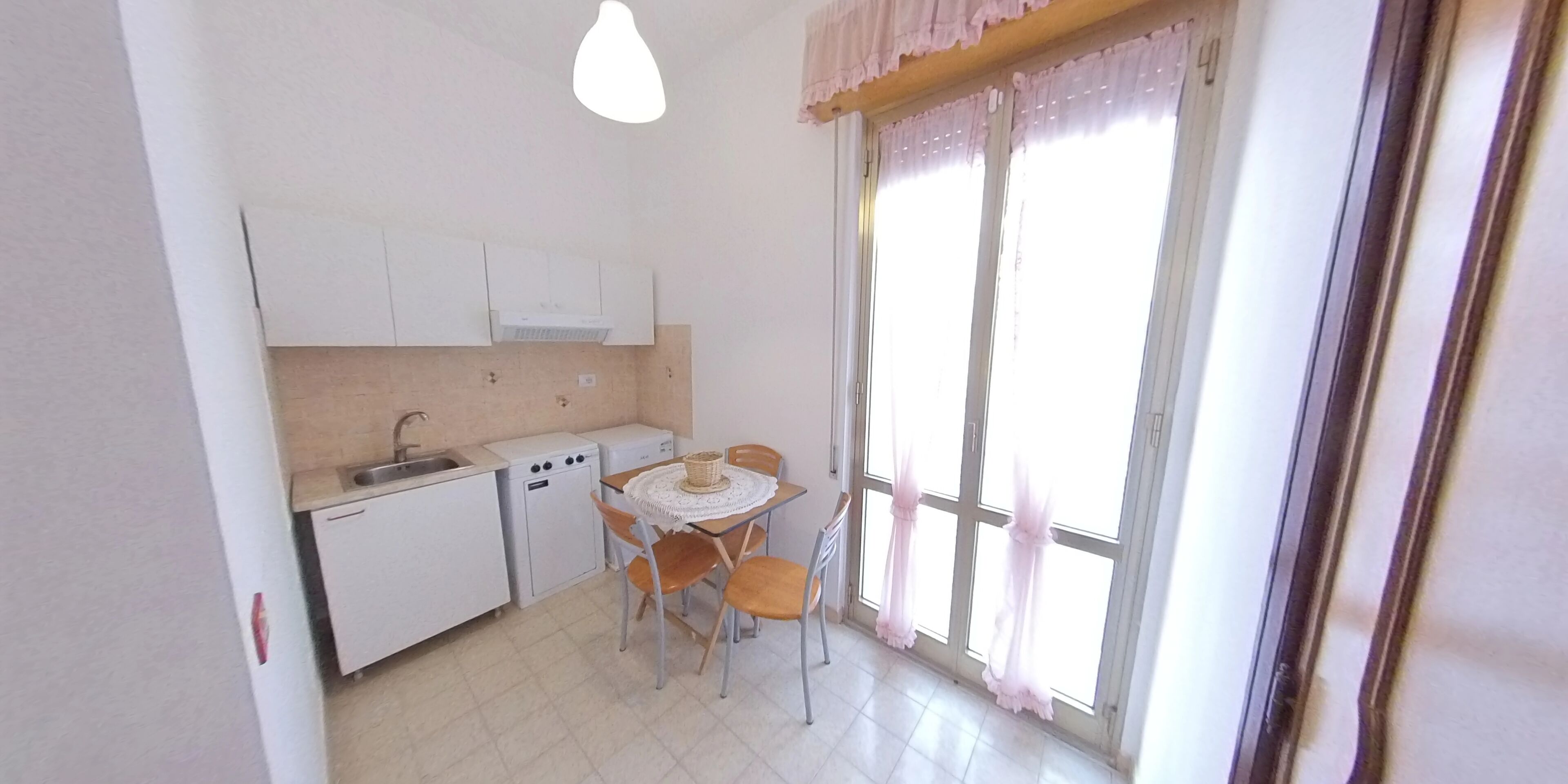 Una cocina compacta con un lavamanos, un refrigerador pequeño y una mesa de comedor con sillas.