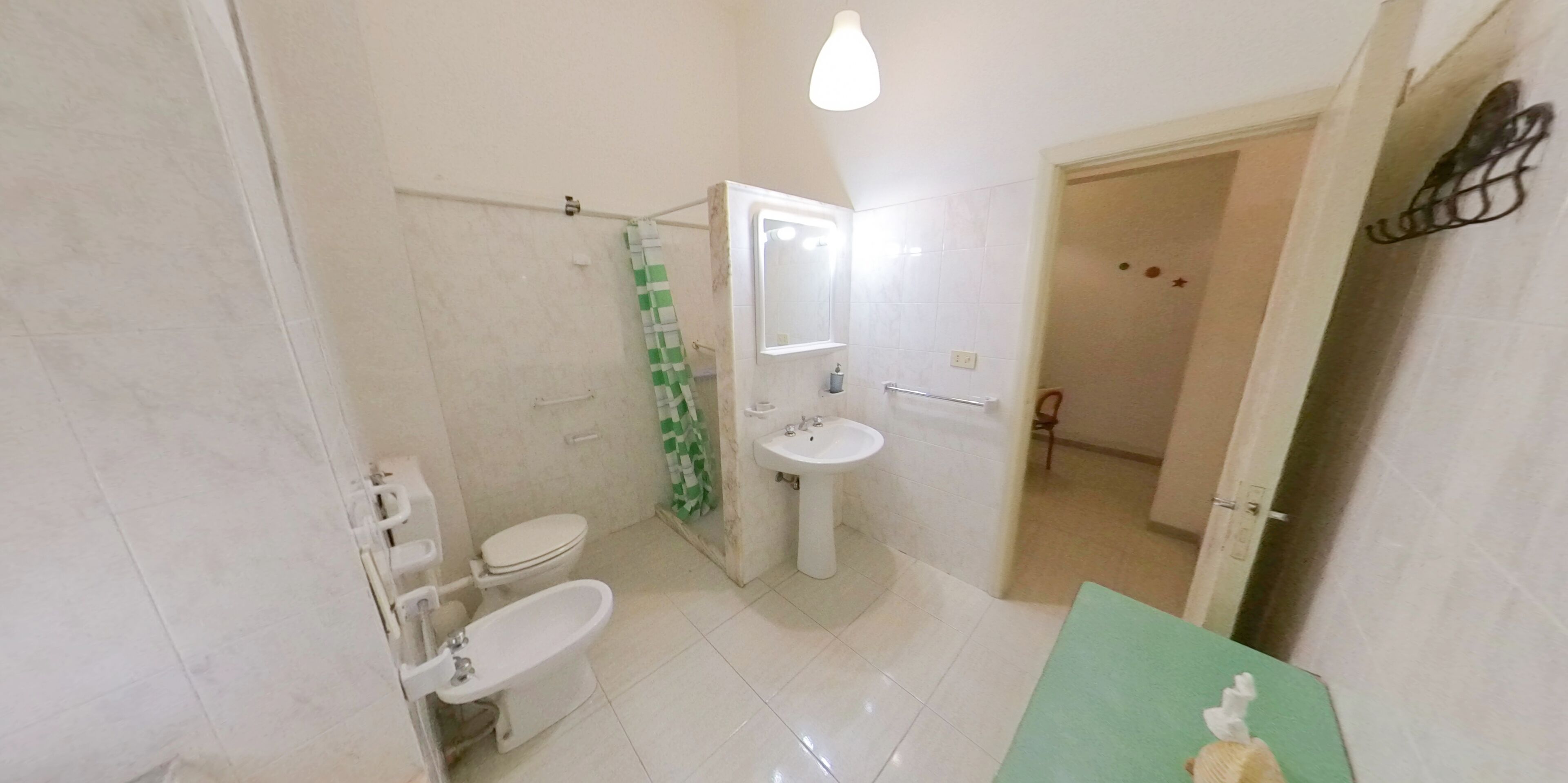 Ein Badezimmer mit Toilette, Bidet, Waschbecken und Duschbereich.