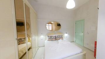 A bedroom with a bed, a wardrobe, a mirror, and a door.