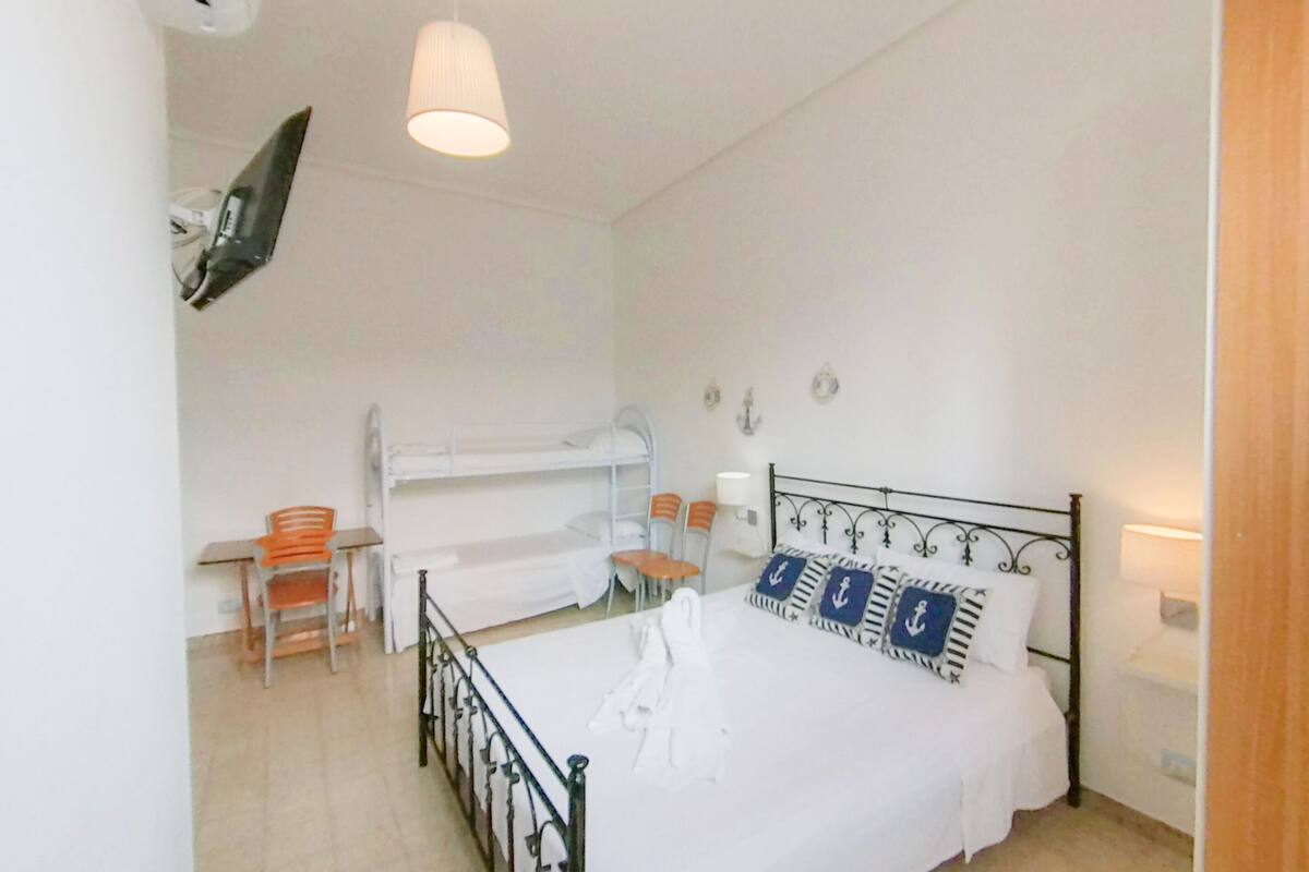 A bedroom with a bunk bed, two chairs, a desk, and a hanging light fixture.