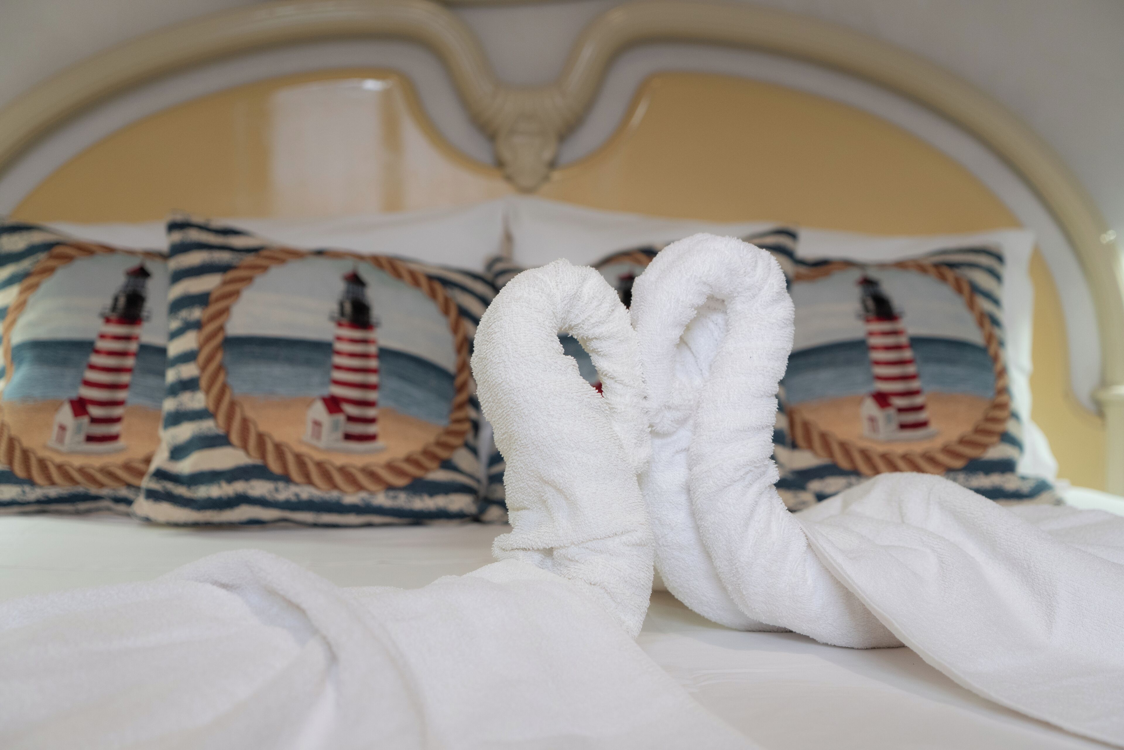 A bed with white linens and two towels arranged in a heart shape.