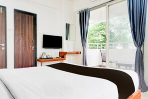 Een hotelkamer met een bed, een televisie, een klein tafeltje met een waterkoker, en uitzicht op het omliggende landschap door een groot raam.