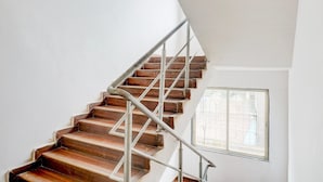 A staircase with wooden steps and metal railings, leading to a landing with a window.