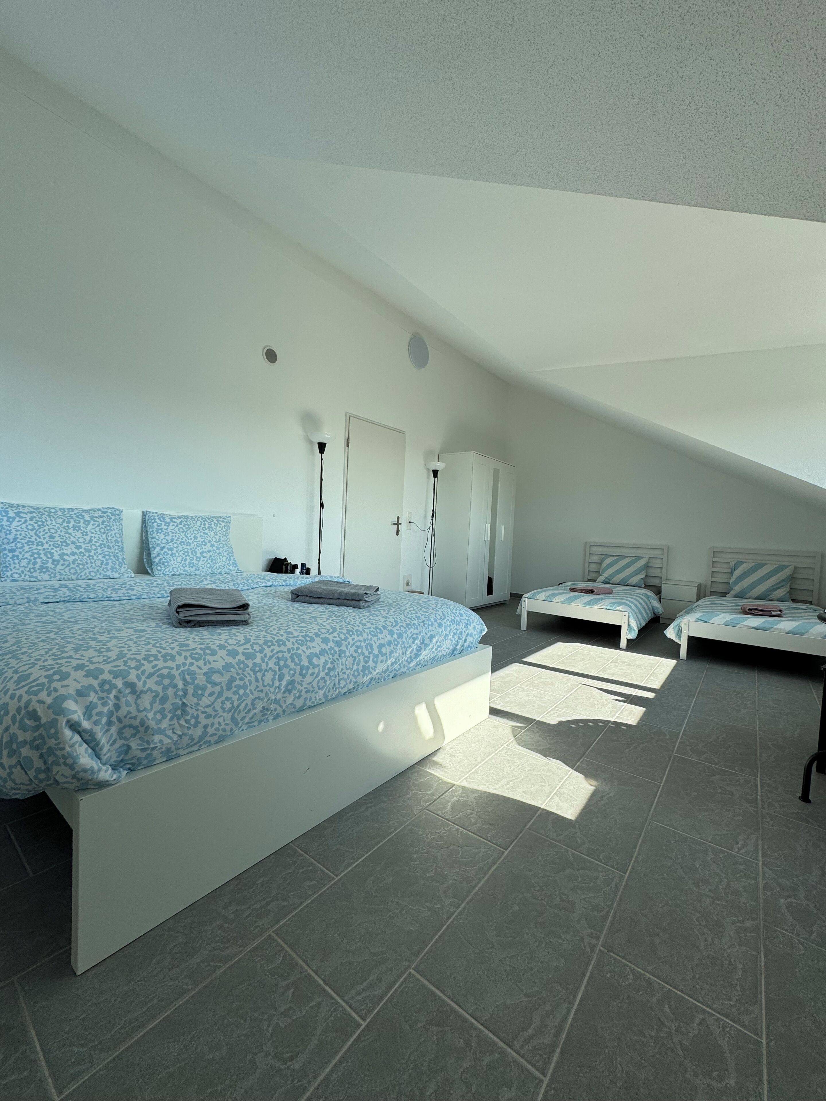 Una camera da letto moderna con un letto grande, due letti più piccoli e un armadio.