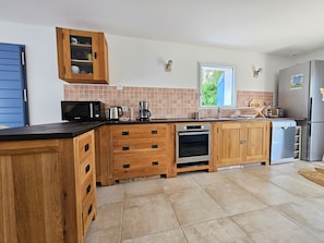 A modern kitchen with wooden cabinets, a built-in oven, a dishwasher, and a refrigerator. - 3-star villa, near the beach, ideal for 4 people (La Faute-sur-Mer)