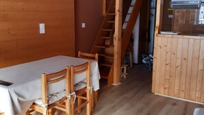 A wooden interior with a dining table and chairs, a staircase, and a kitchenette area. - Mezzanine Studio 4 Pers, Parking, Near Châtel Center (Châtel)