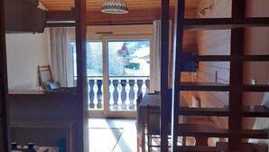 A wooden interior with a balcony, a ceiling light, and a view of a snowy landscape. - Mezzanine Studio 4 Pers, Parking, Near Châtel Center (Châtel)