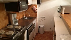 A compact kitchen with a stove, oven, sink, and microwave.