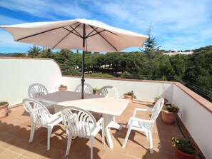 A terrace with a table and chairs, an umbrella, and potted plants. - Apartment in S'Agaró for 5 persons with terrace (S'Agaró)