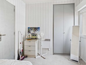 A bedroom with a bed, a dresser, a fan, a door, and a painting. - 2-room apartment beachfront, direct beach access, near shops (Le Grau d'Agde)