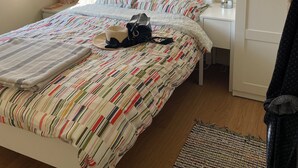Una cama bien hecha con ropa de cama a rayas, una lámpara de noche y una mesita con lámpara.