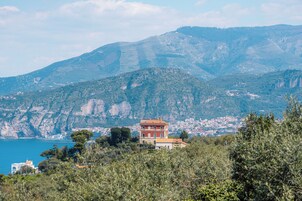 A coastal town with a prominent building on a hill, overlooking the sea and a densely packed town below.