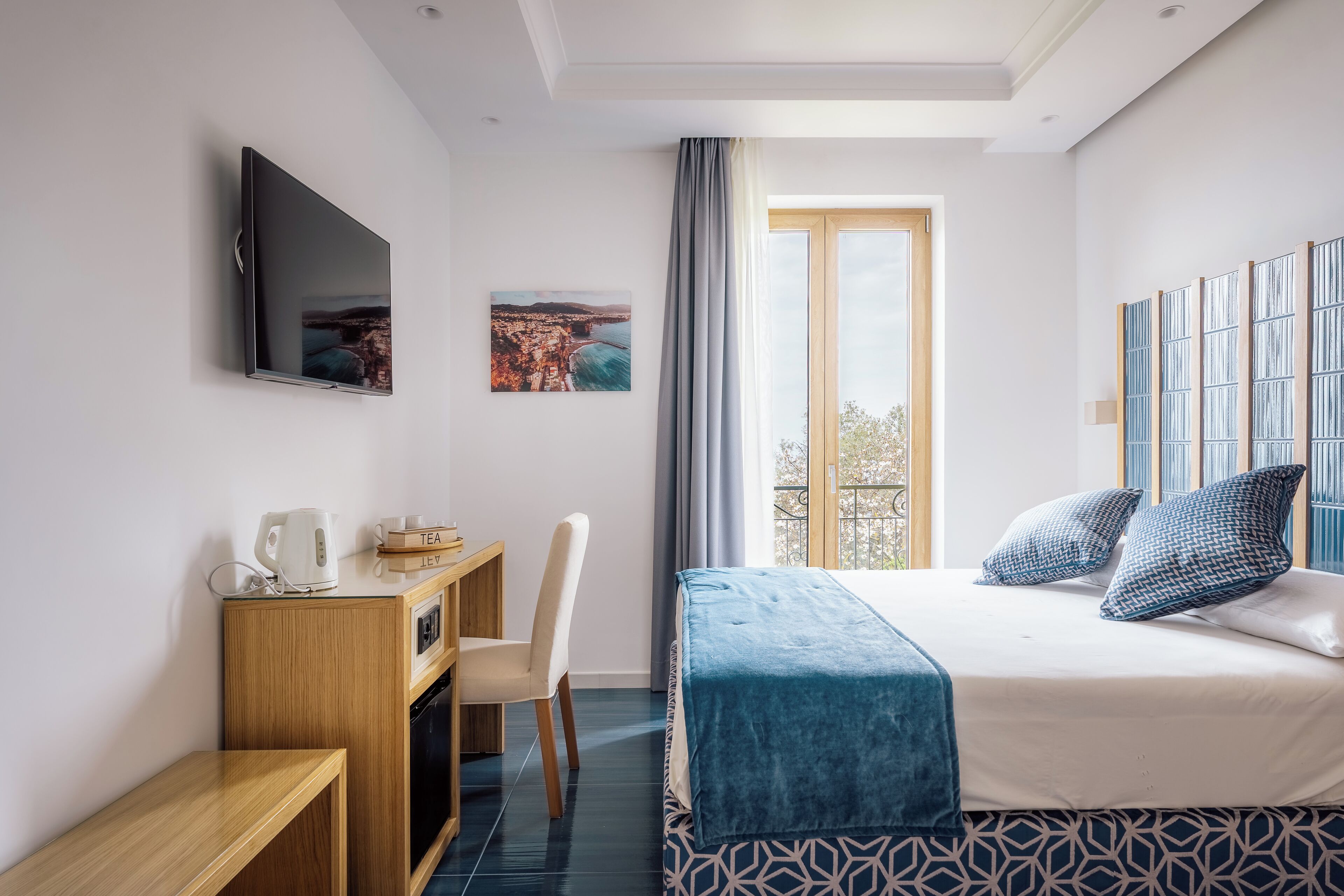 Une chambre d’hôtel avec un lit, un bureau et une chaise, une télévision et une fenêtre avec des rideaux.