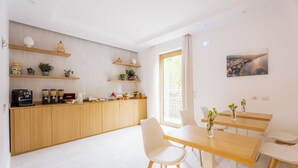 A modern kitchen with wooden cabinets, a dining area with a table and chairs, and a large window with a cityscape view. - Relais S. Francesco  (Sorrento)