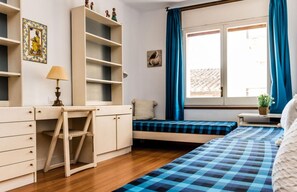A bedroom with a bed, a desk, shelves, a window with curtains, and a small plant.