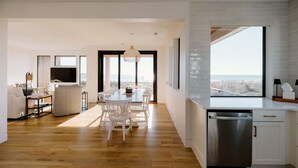 Un saló modern amb zona de menjador, cuina amb finestra gran i vistes a la ciutat.
