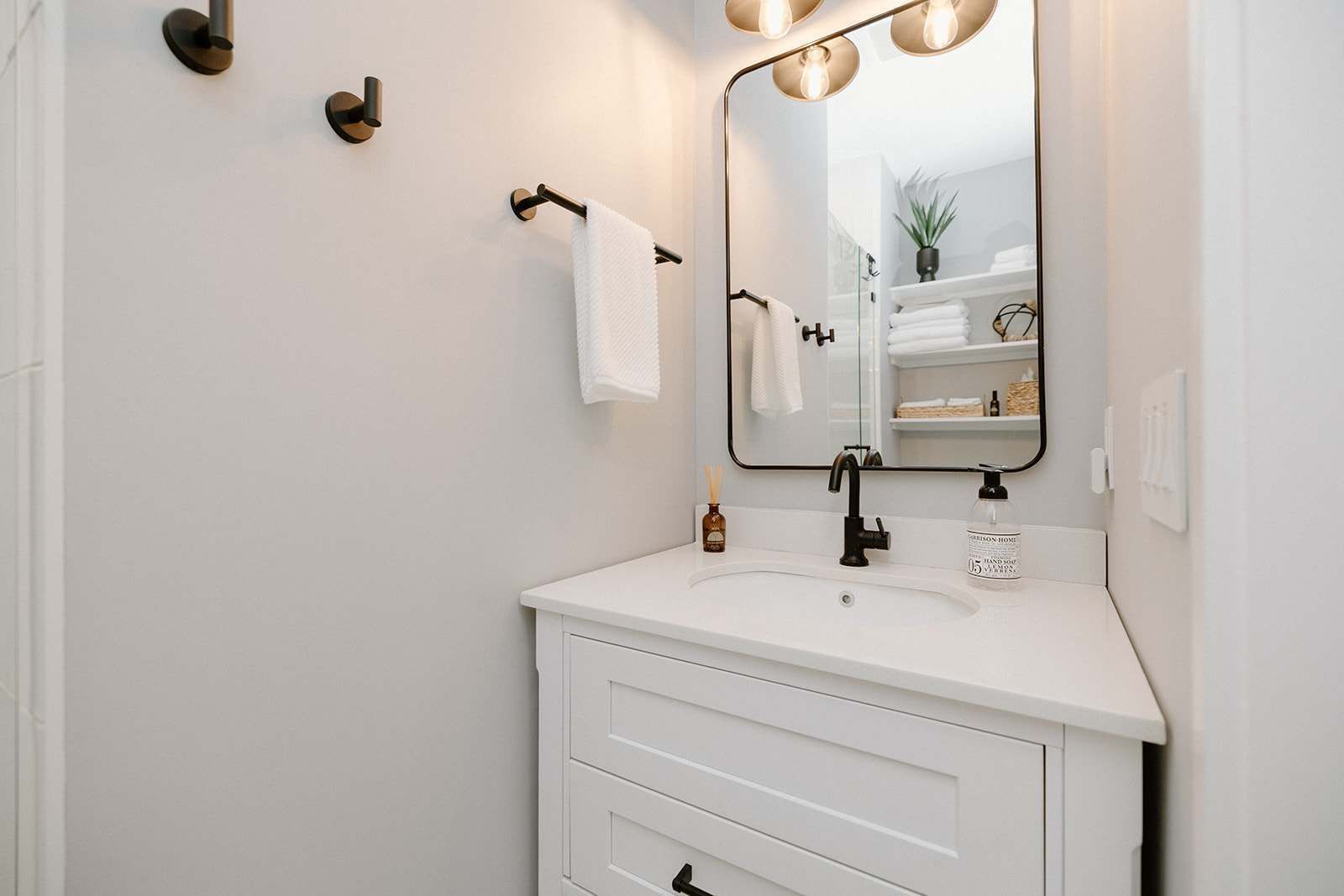 A modern bathroom with a white vanity, a large mirror, and a towel rack.