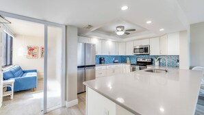 Een moderne keuken met witte kasten, een groot eiland en een blauwe achterwand.