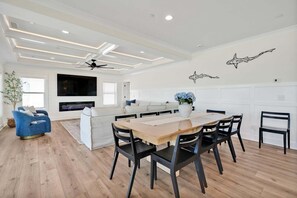 A modern living room with a dining area, white walls, and a fireplace.