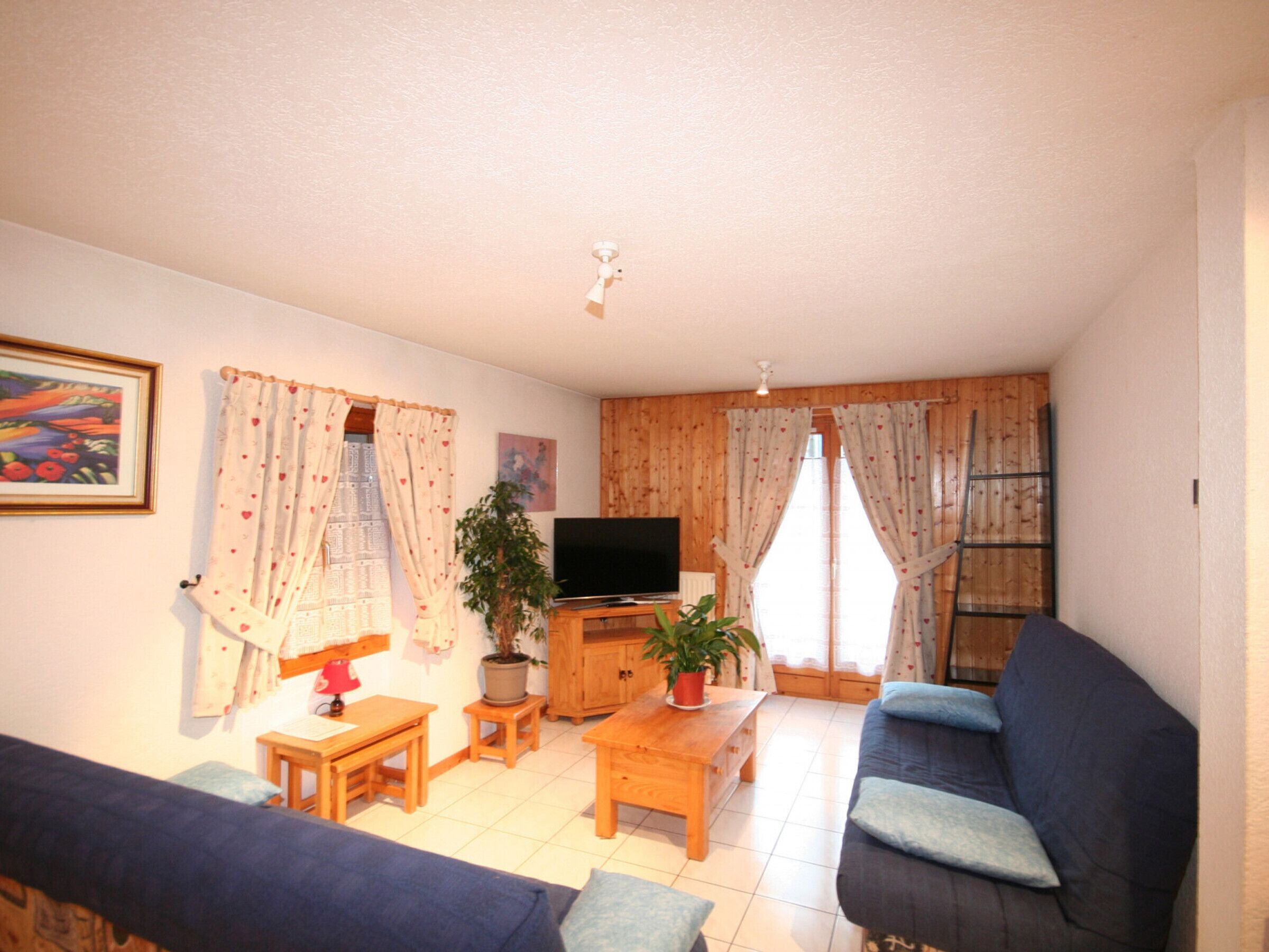 Una sala de estar con un sofá, una mesa de centro, un televisor y una planta.